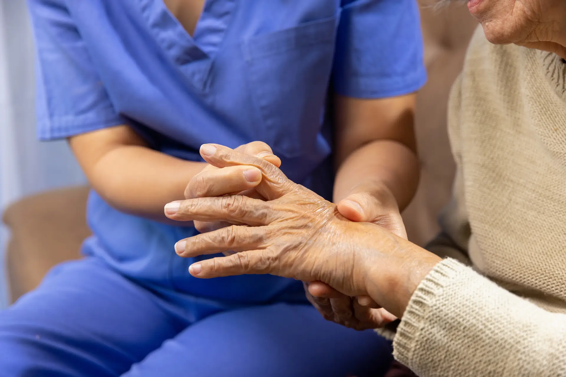 Caregiver massaging finger of elderly woman in painful swollen gout .
