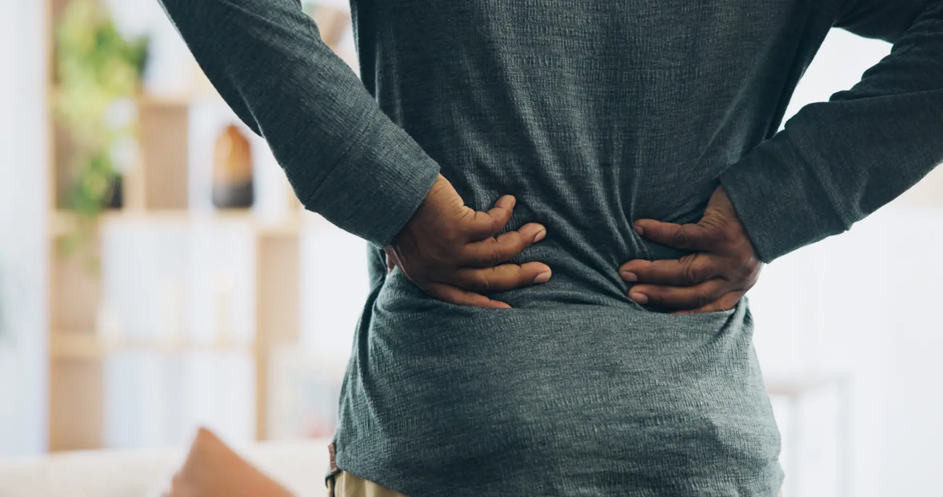 Back and injury with pain for bad posture, muscle tension or herniated disc at home. Closeup, hands and pressure with sore spine, cramp or ache for fibromyalgia or discomfort at house