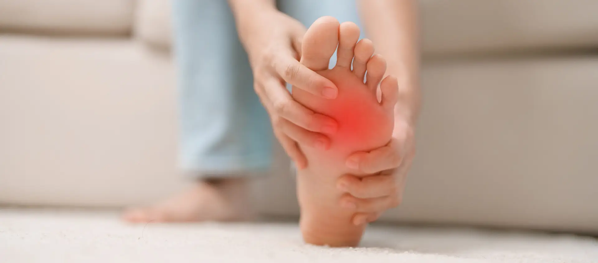 woman having barefoot pain during sitting on couch at home. Foot ache due to Plantar fasciitis and waking longtime. Health and medical concept