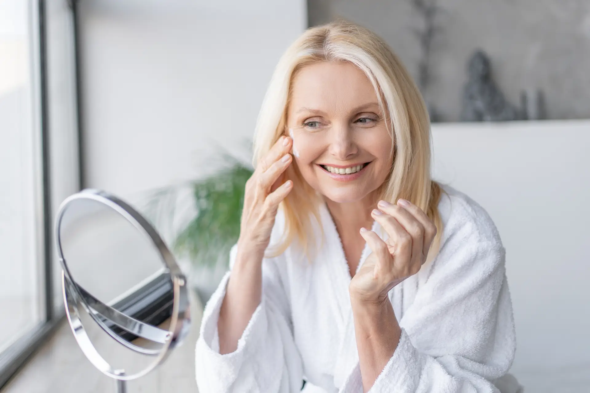 Skincare, portrait and adult woman with cream in bathroom, wellness and anti aging benefits in morning. Home and female person with application for cosmetics, beauty treatment and face moisturizer