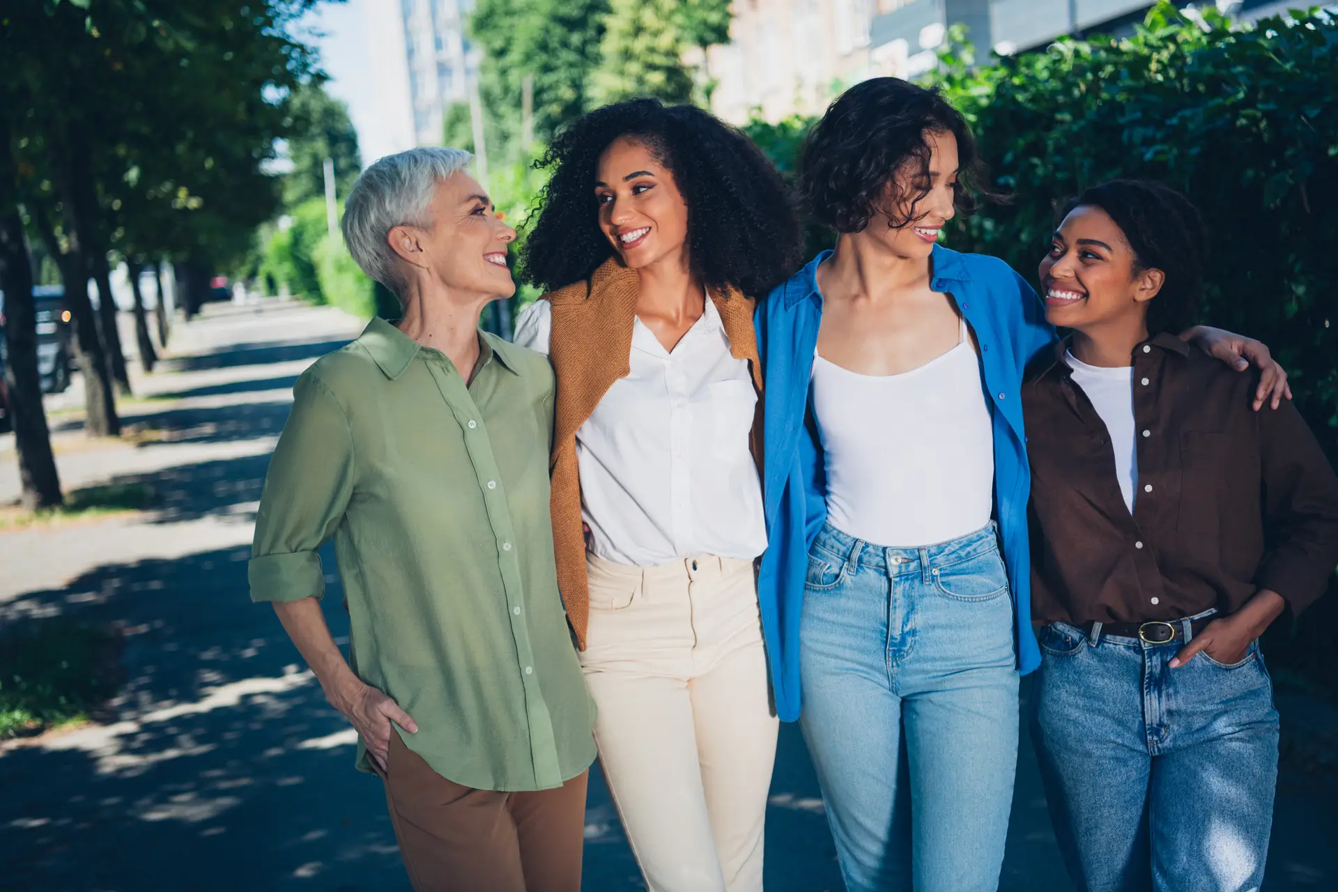 Photo portrait of happy multi generational women teamwork hugging together multiracial friends outdoor city park