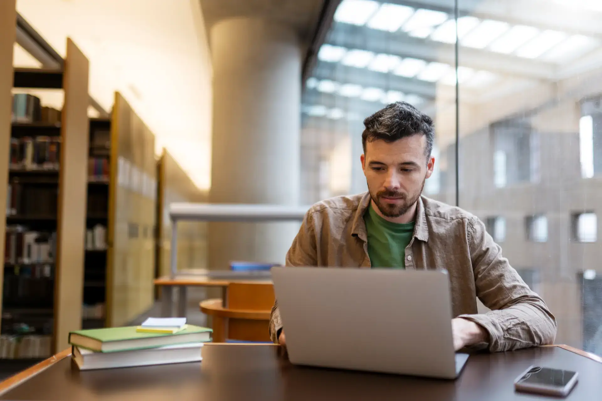Latin student studying, using laptop, learning language, exam preparation sitting in library