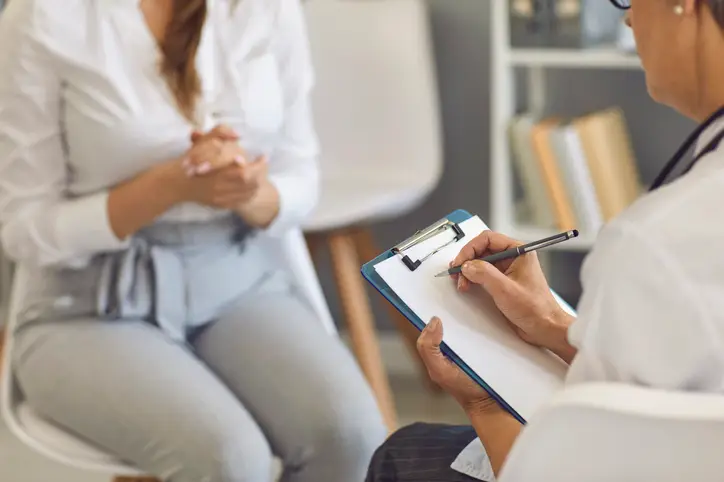 Doctor writes a prescription to a woman patient at a medical consultation in a clinic.